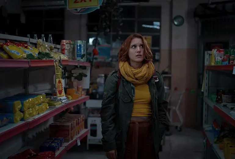 una mujer asustada camina por los pasillos de un supermercado pequeño de noche