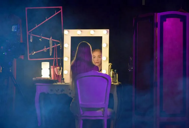una mujer rubia se mira al espejo en su camarin durante una jornada de grabacion